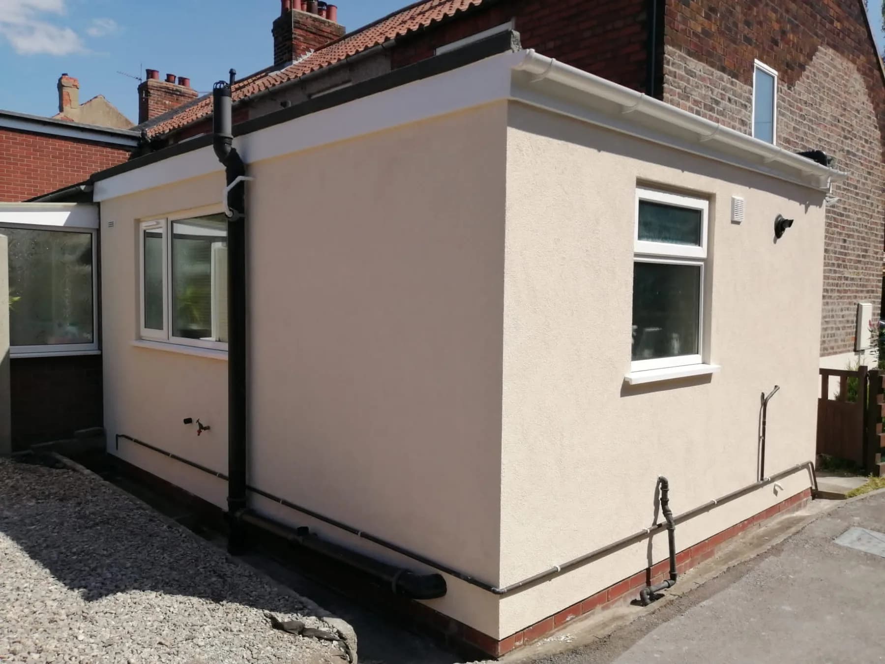 Rear extension finished in cream silicone render — clean smooth finish on brick outbuilding