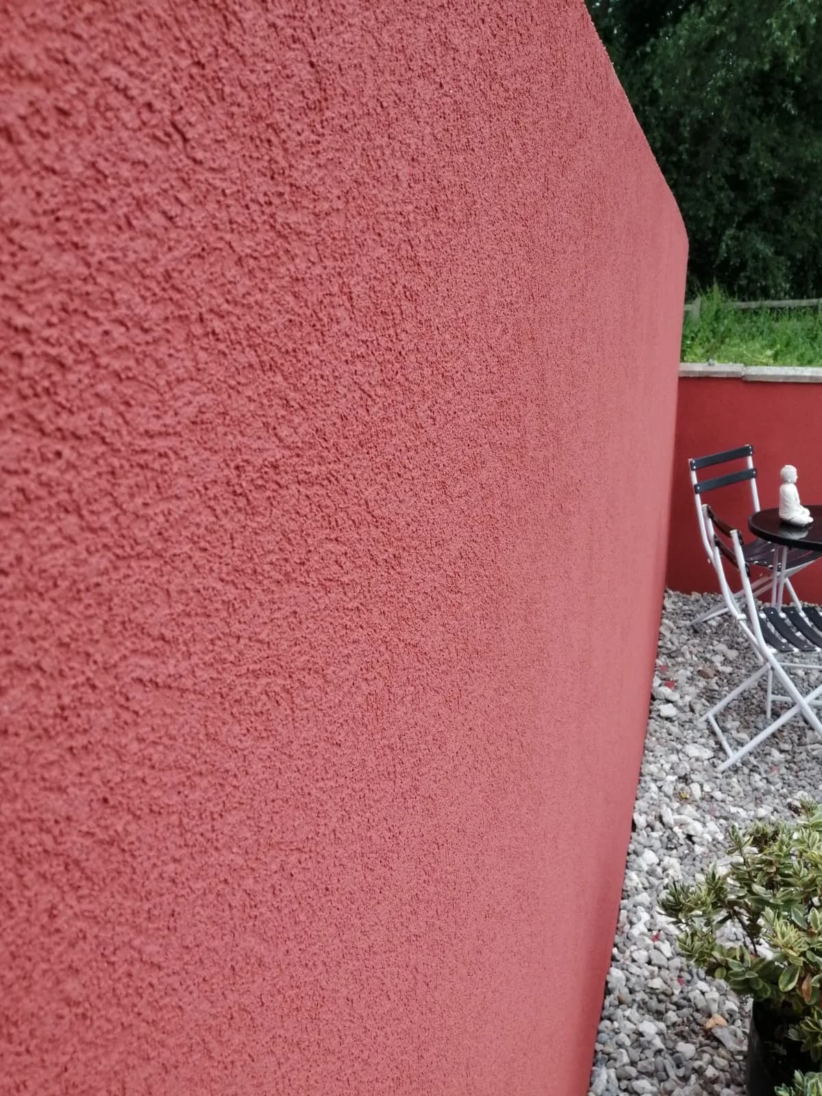 Rendered garden wall in deep red silicone — close-up showing fine texture quality